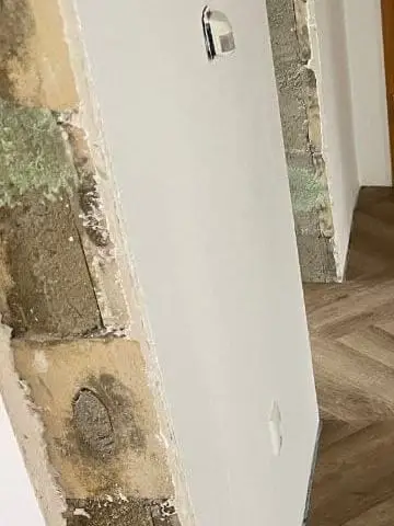 Nahaufnahme einer geöffneten Wand mit freiliegendem Mauerwerk, Mörtel und der Schnittkante des alten Oberflächenaufbaus