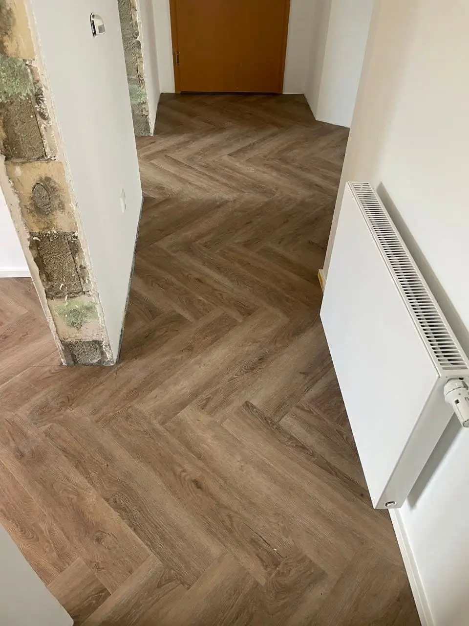 Flur mit geöffneter Wandlaibung, freiliegendem Mauerwerk und bereits fertig gespachtelten Wandflächen daneben