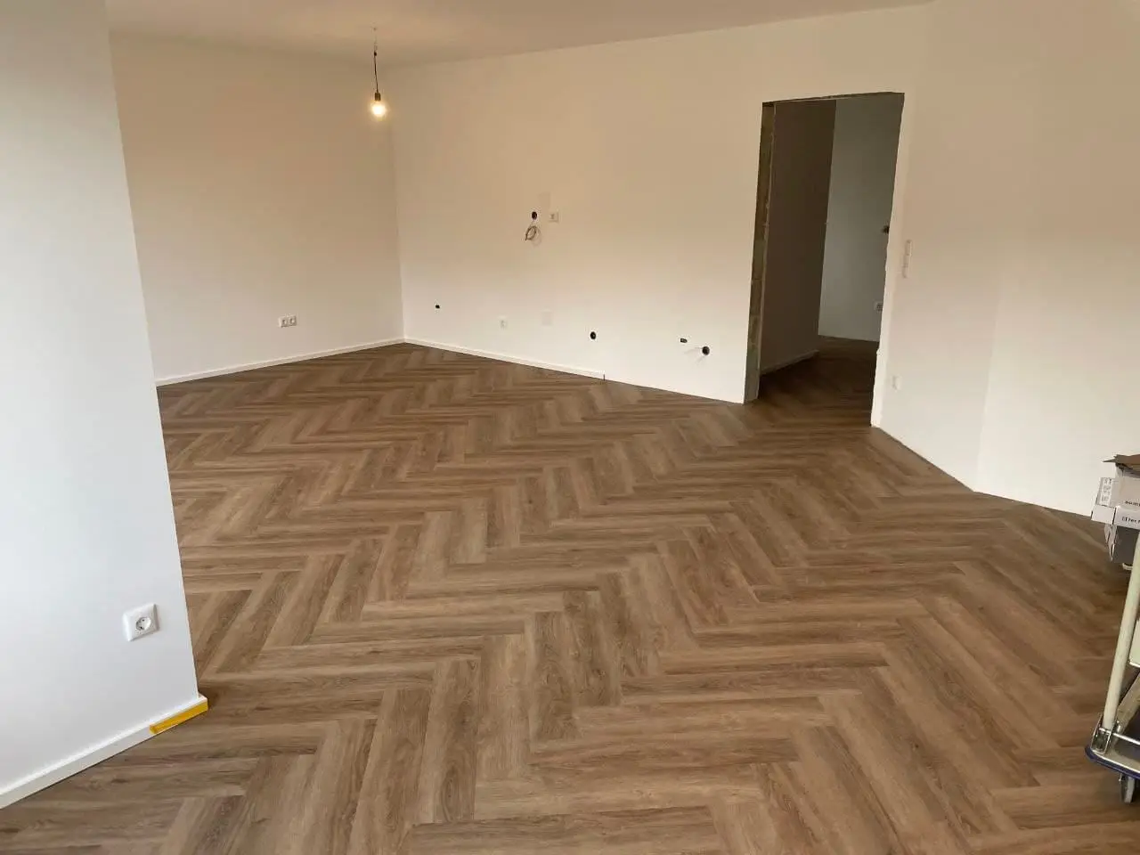 Leerer Wohnraum mit fertig gestrichenen Wänden und Decke, im Türdurchgang ist eine Laibung noch offen