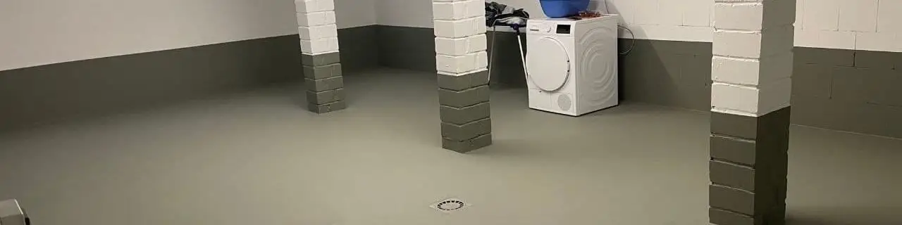 Sockelbereich eines hellen Kellerraums mit farbig abgesetzter Wandzone über dem beschichteten Boden