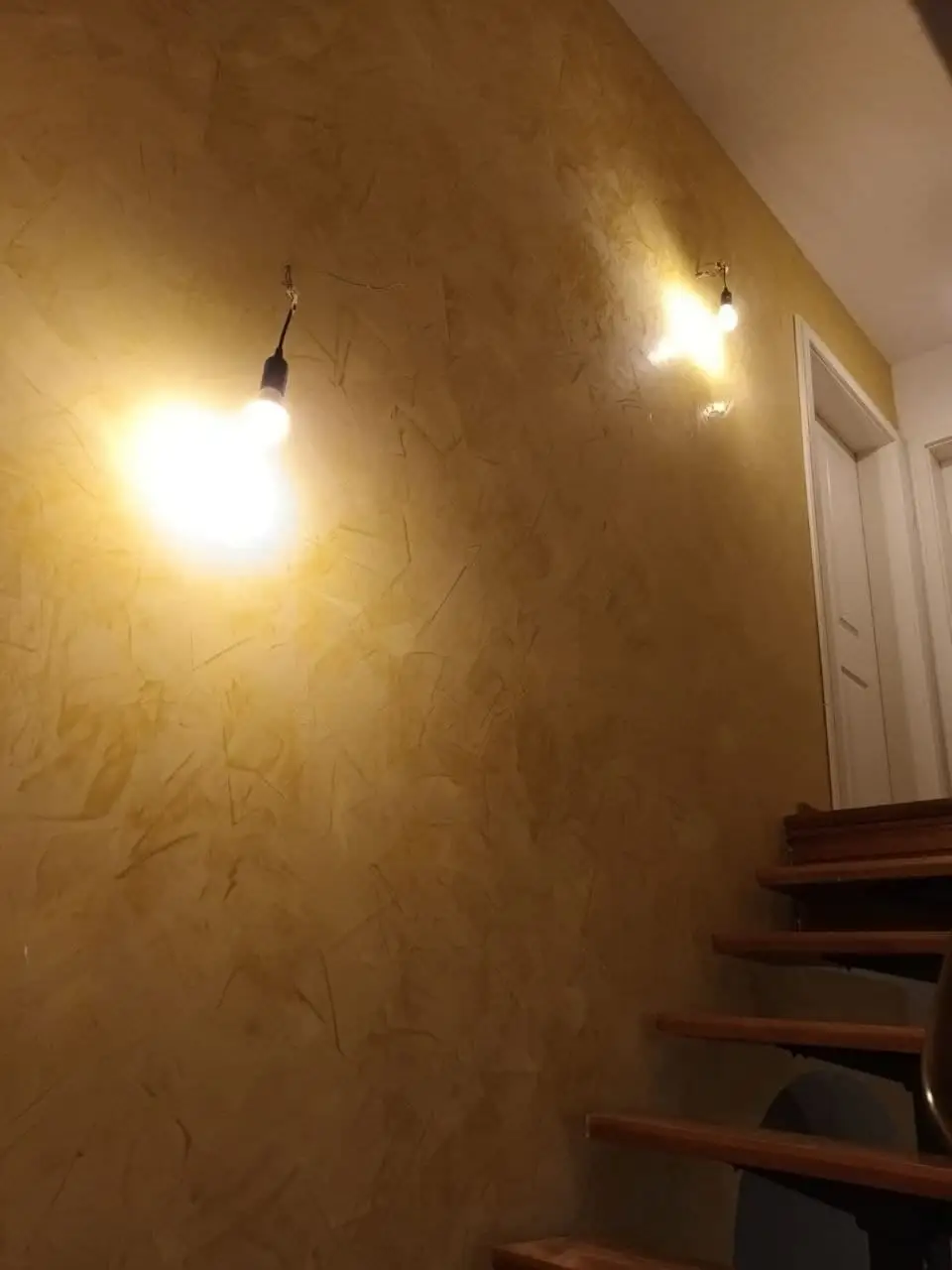 Treppenhauswand mit lasierter, strukturierter Oberfläche in warmem Ton, seitlich beleuchtet